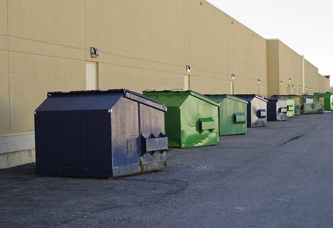 a construction worker empties a wheelbarrow of waste into the dumpster in Boley